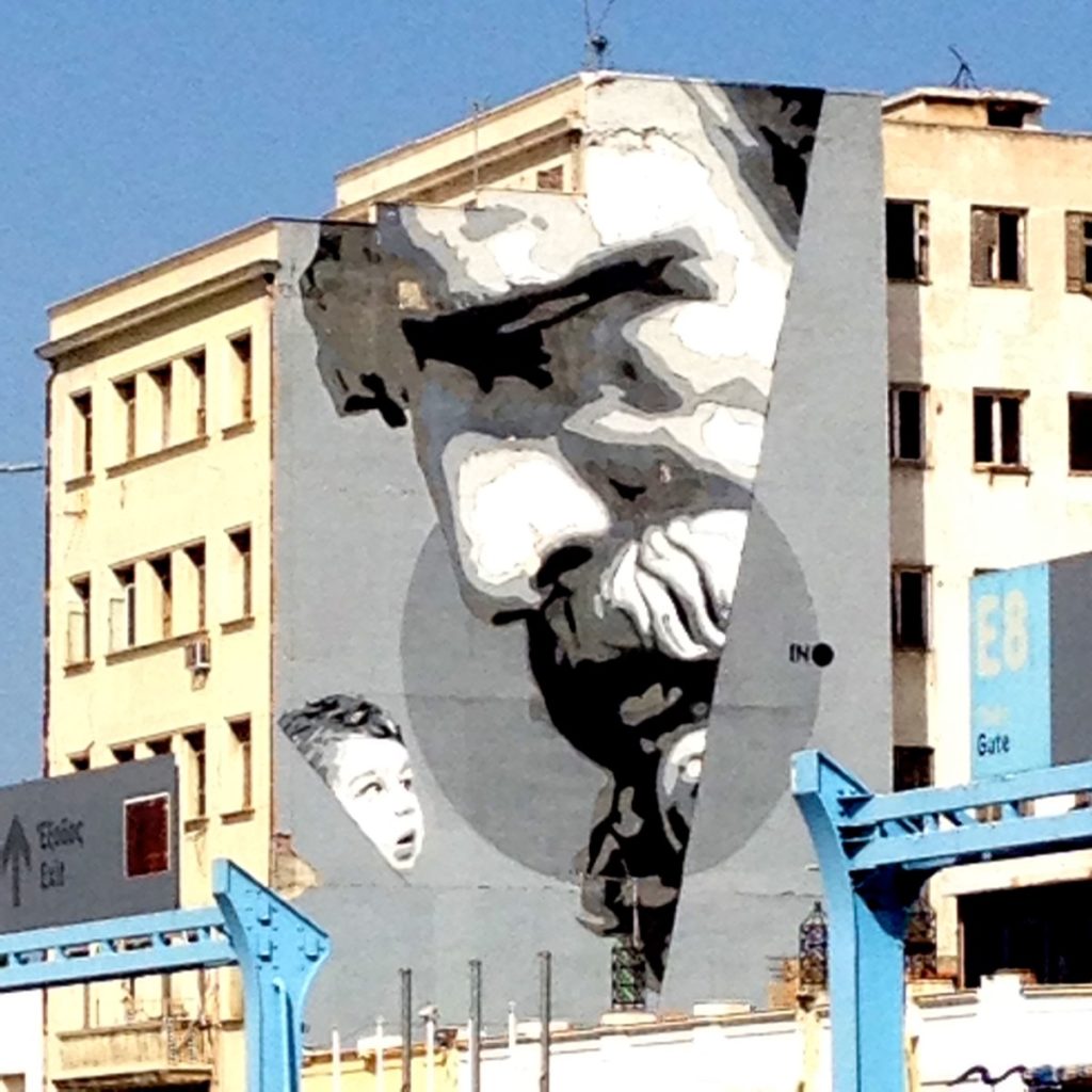"We Have The Power" - "Wissen ist Macht": ein Wandbild von iNO aus dem Jahr 2015 im Hafen von Piräus. Es zeigt ein Kind, das zu einem Portrait des antiken Philosophen Demokrit aufsieht (09/2020, Piräus, Attika, Griechenland).