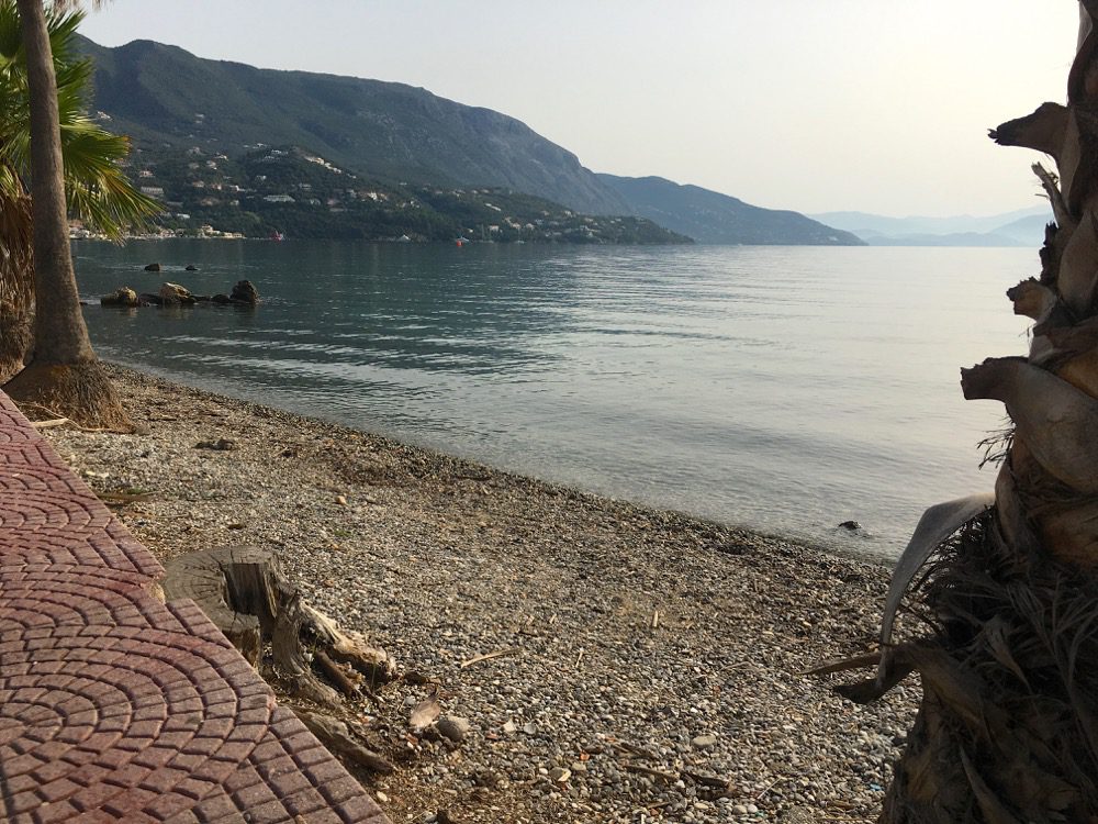 Wie ausgestorben: Der Hafen und der Strand in Ipsos an der Ostküste von Korfu (Korfu, Ionische Inseln, Griechenland, 18.08.2022).